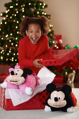 Smiling girl opening a Christmas gift containing the Mickey Mouse and Pink Minnie Mouse Pillow Pets.