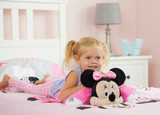 Little girl smiling while cuddling the Pink Minnie Mouse Pillow Pet unfolded into a soft plush pillow.