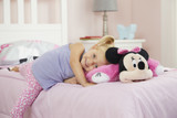 Little girl smiling resting on the Pink Minnie Mouse Pillow Pet unfolded into a soft plush pillow.
