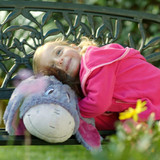 Lifestyle Image o little girl smiling while cuddling the Eeyore Pillow Pet.