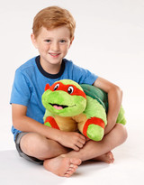 Lifestyle image of little boy smiling while holding the Raphael Pillow Pet.