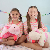 Girls smiling while cuddling the Strawberry Cow and Wiggly Pig Pillow Pets.