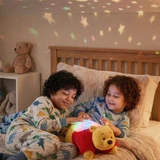 Winnie the Pooh Sleeptime Lite lifestyle image with two little boys playing with the product in a bedroom with the night light shining rainbow stars above