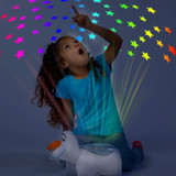Little girl sitting with the Olaf Sleeptime Lite while looking up at the colorful stars projected onto the ceiling.