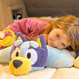 Little girl lying on the Bluey Pillow Pet unfolded in pillow form.