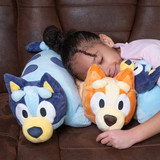 Little girl cuddling the Bluey and Bingo Pillow Pets.