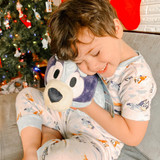 Little boy smiling hugging the Bluey Pillow pet.