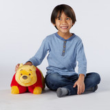 Little boy smiling sitting beside the Winnie the Pooh Pillow Pet.
