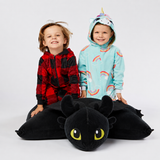 Lifestyle image of two kids smiling while sitting on the Jumbo Toothless Pillow Pet, showcasing its extra-large plush design.