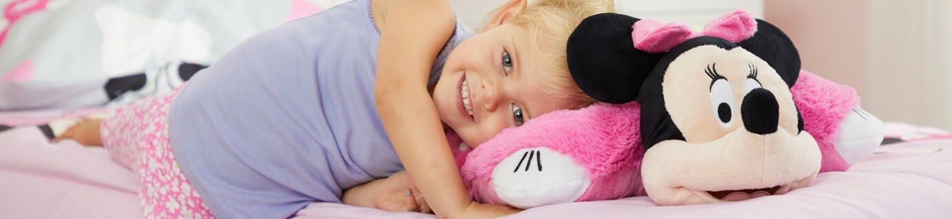 Little girl smiling while laying on her cute pink Minnie Mouse Pillow Pet.