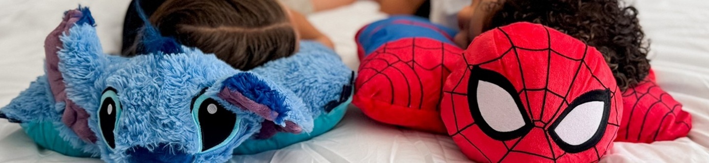 Two children sleeping on a comfy Spider-Man Pillow Pet and a Stitch Pillow Pet.