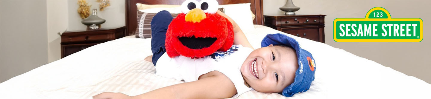 Little kid on a bed with an Elmo Pillow Pet