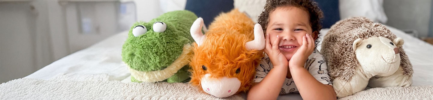 A little boy surrounded by the cutest and comfiest Pillow Pets.