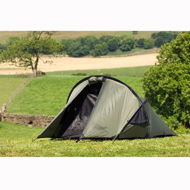 Snugpak Scorpion 2 IX olive tent pitched on grass with front door fly panel open showing Snugpak branding on flysheet body, No-See-Um mesh inner tent visible inside, and opposing aluminum pole design overhead
