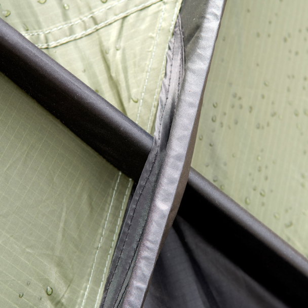 Snugpak Scorpion 3 IX olive close-up of door opening showing rolled mosquito net bundled at top of pole arch with dark mesh inner tent and zipper track visible below
