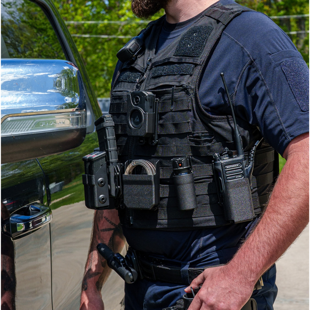 Law enforcement officer wearing a plate carrier with the Zero9 radio case mounted on the front, outdoors