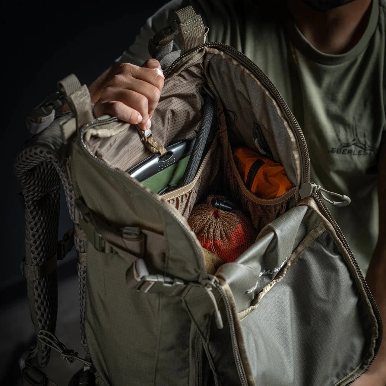 Open backcountry pack showing a hydration reservoir, dry bag, and organized gear
