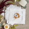 Custom embroidered cocktail napkins. Set of 4. Customized with a monogram initial in eggplant purple thread and wheat colored pampas grass. Background has flowers and spoon.