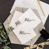 White handkerchiefs monogrammed with a handwritten signature in black embroidery thread. Shown with florals and embroidery thread.