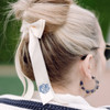 Monogrammed hair ribbon shown in women's hair. Cream bow with navy blue embroidery thread.
