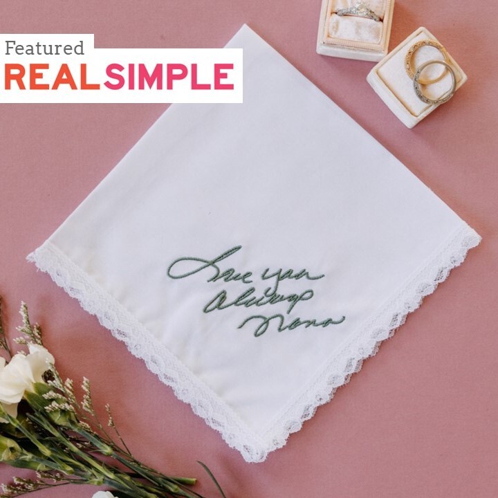 Handwritten embroidery on lace white handkerchief for women. Bridal flowers, wedding rings on pink background.