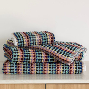Stacked Miami Pom Pom towels including bath towel, bath mat, and hand towel in multicoloured upcycled cotton/polyester with textured pom-pom pattern. Stacked Miami Pom Pom towels including bath towel, bath mat, and hand towel in multicoloured upcycled cotton/polyester with textured pom-pom pattern.