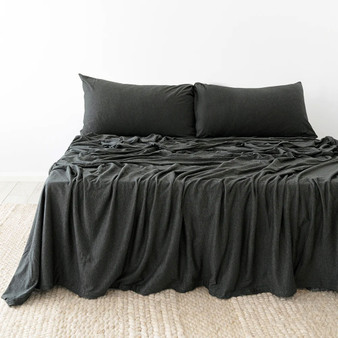 Charcoal Bambury BedT Organica sheets styled on a made bed, highlighting the smooth knitted finish and breathable drape across pillows and mattress.