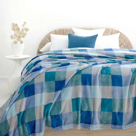 Blue and green check plush blanket styled on a bed with matching pillow shams
