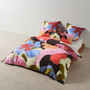 Glinda quilt cover by Linen House styled on a bed, showcasing abstract hand-painted floral design in vibrant colours