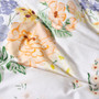 Close-up of Lyra quilt cover by Linen House highlighting apricot, honey, green, and purple floral accents