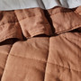 Close-up of Nimes clay coverlet highlighting quilted pure linen texture and soft pre-washed finish.