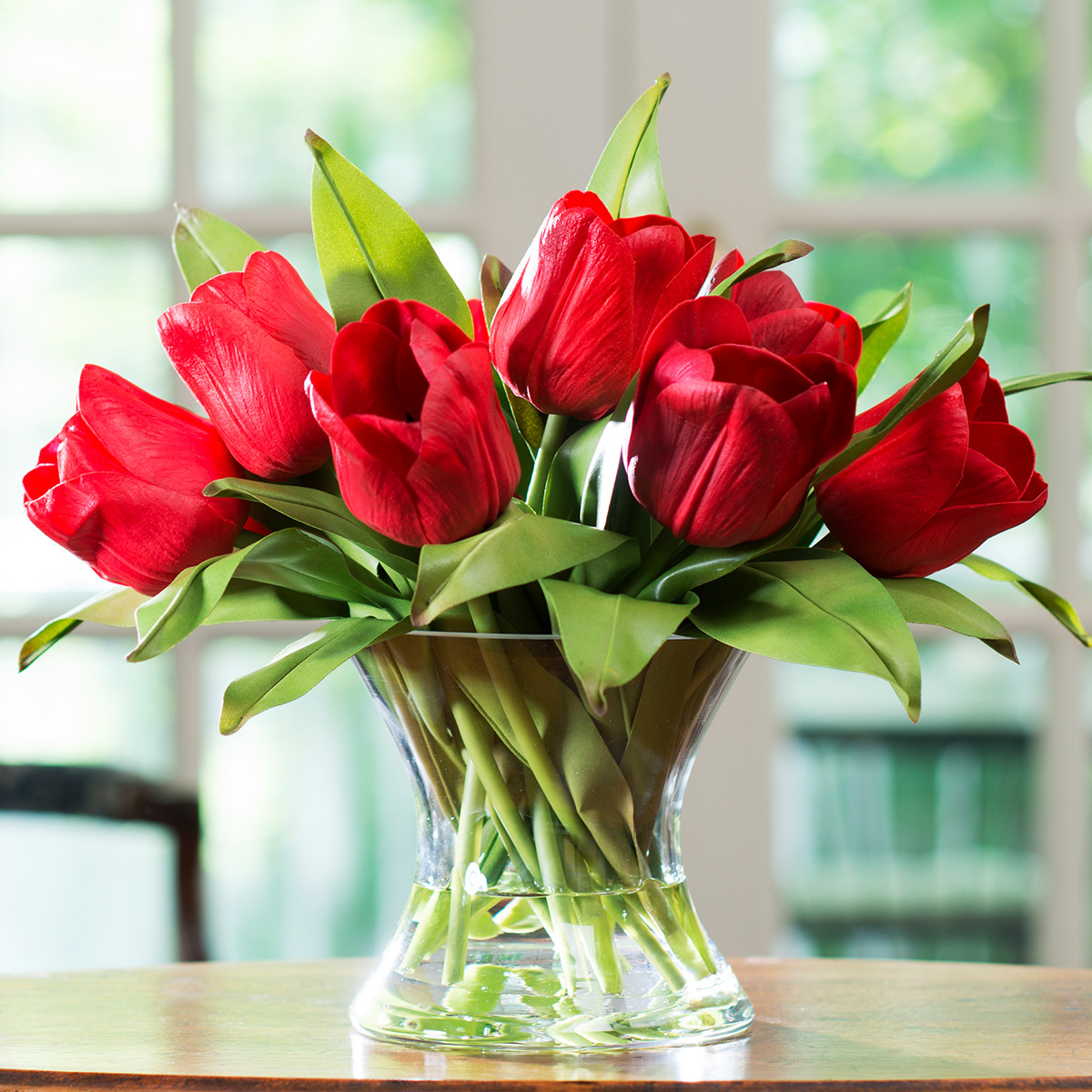 Red tulip silk flower arrangement in glass vase