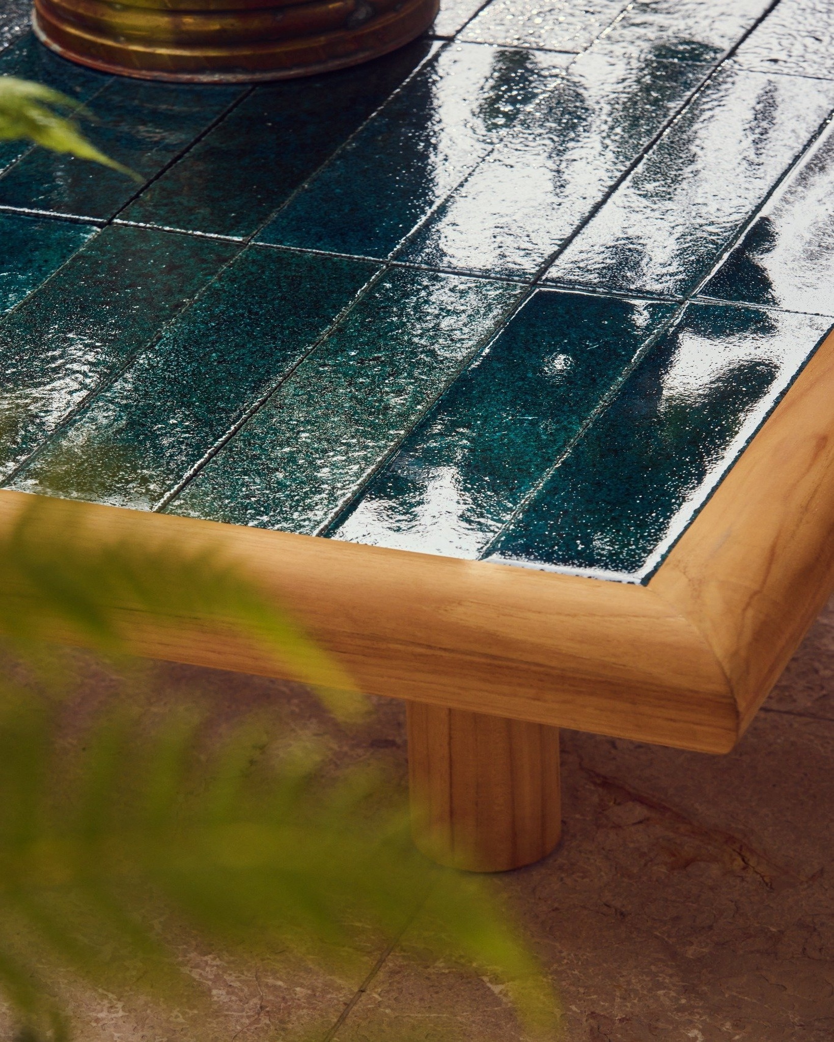 Close-up of Tulum outdoor coffee table with solid teak frame and glazed lava stone tile top in ocean teal.
