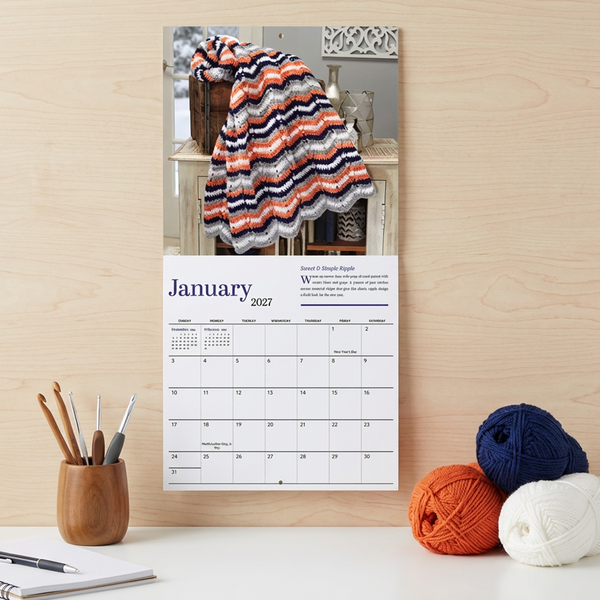 Image of the 2027 Treasury of Crochet Afghans  Calendar hung on a wall above a desk.
