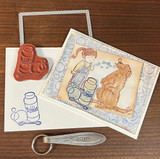 Soft watercolor card with an embossed bubble frame showing Emma, her dog and the bubble bottle, next to the red rubber stamp and a stamped bottle.