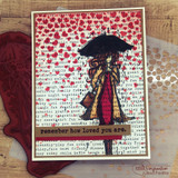 The umbrella girl on a red heart-print card over script paper — 'remember how loved you are.'