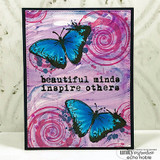 Card with two butterflies stamped in turquoise over pink and purple swirls on a marbled lilac background.
