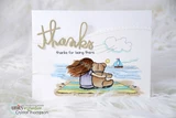 Card with a small child and teddy bear seated on the sand under a blue sky with a sailboat, a die cut 'thanks' word and a small thanks for being there sentiment.