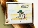 Card with the beach girl in a green hat on a pale watercolor beach, 'BE HAPPY and smile' stamped above her, matted on brown with a real seashell alongside.
