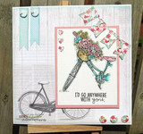 Card with the flower-basket bicycle on a coral panel over woodgrain paper, stamped 'I'D GO ANYWHERE WITH you.' beside a second uncolored bicycle.