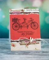 Coral red card with the tandem bike stamped in black, 'Thanks for being my friend!' below, torn floral strips and twine with a wood heart