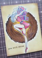 Card with a wood slice circle behind a girl in pink and blue with feathered butterfly wings, mounted on a purple plaid background.