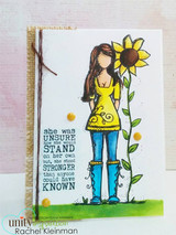 White card on burlap with the girl colored in a yellow tunic and blue boots beside two sunflowers, yellow enamel dots and a block of type about standing stronger at the left.