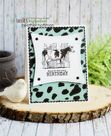 The Holstein cow framed by a cow-spot border on a mint panel over woodgrain — 'Herd it was your birthday.'