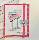 A pink polka dot card with two stemmed wine glasses stamped and watercolored in soft pink and mint, with the sentiment 'together is the best place to be' and a heart die cut.