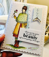 Card with Beatrix colored in a green poncho, mustard coat and plaid skirt holding a pink rose, with the beauty sentiment on a white label and gem-studded banners.