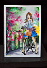 Watercolor card of the cycling girl riding through a haze of pink blossoms with a "beautiful ride" sentiment.