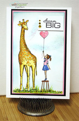 Card with a golden giraffe and a girl in a blue skirt on a stool reaching for a pink heart balloon under a watercolor sky, with the 'dream BIG' sentiment