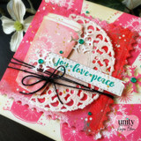 Card with a pink snowflake travel mug on a doily over a bright pink background and 'joy love peace.'