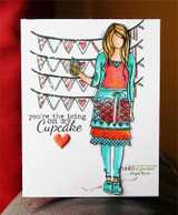 Card with Cari colored in a teal cardigan, coral top and red patterned skirt holding a cupcake under the bunting, beside 'you're the icing on my cupcake' and a red heart.